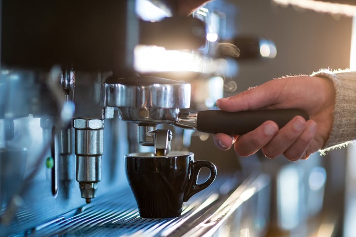 Waiter making cup of coffee at counter in kitchen at cafx92xA9